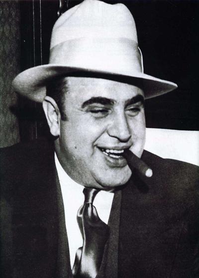 Fotografia clássica de Al Capone, o “Scarface”. Créditos: Getty Images. al capone fumando charuto de chapéu panamá
