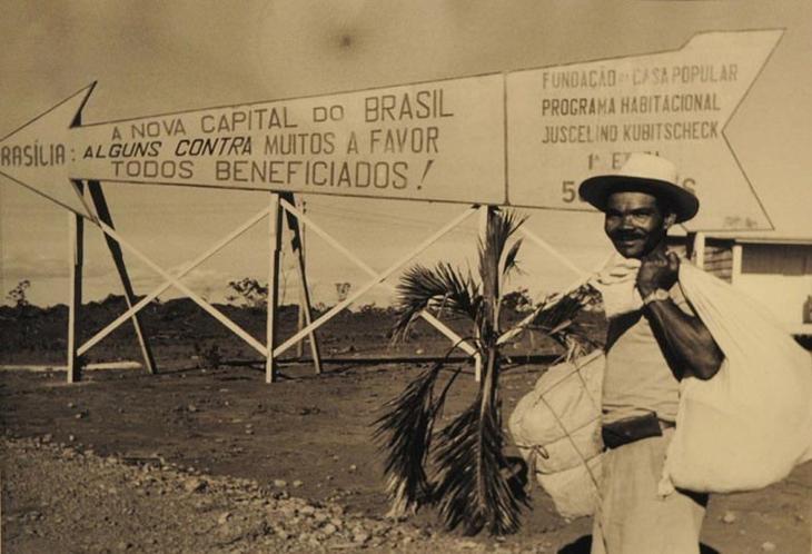 candango na frente da placa indicando onde brasília foi construída