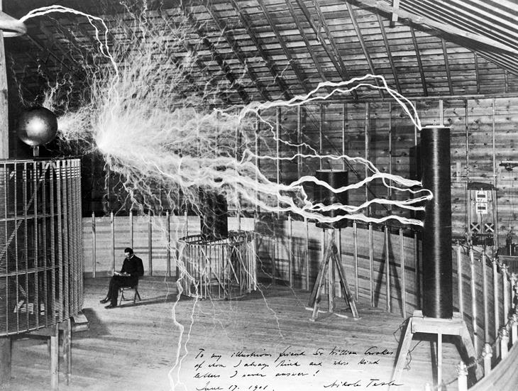 Nikola Tesla em seu laboratório ao lado do seu Transmissor de Ampliação
