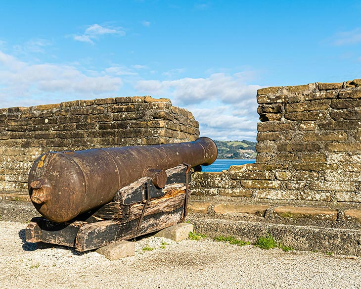 Canhão antigo em ameia de fortificação em alusão à arma de pólvora usada durante a Guerra dos Cem Anos.